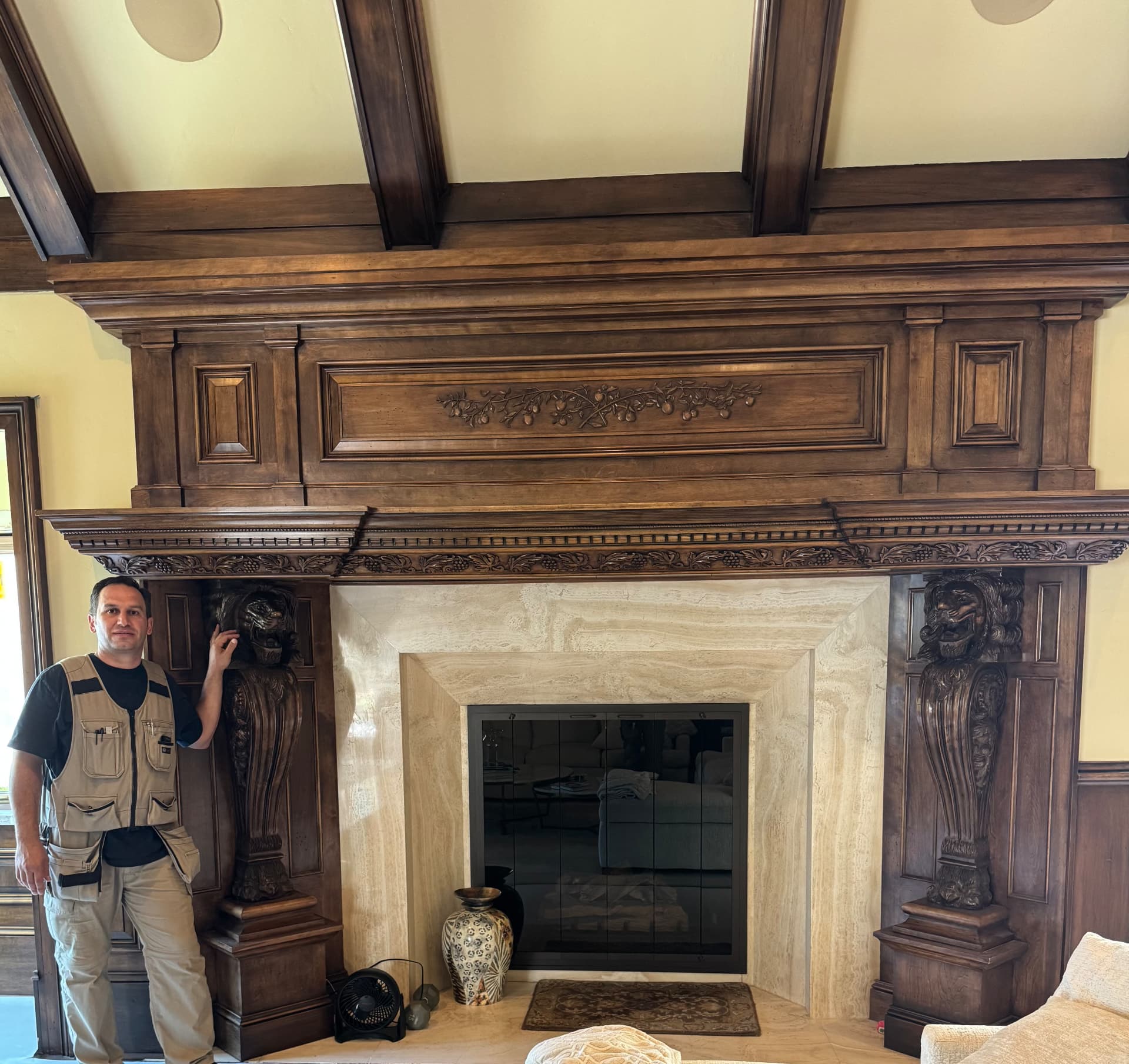 Elbron, owner of Rome Fine Homes, beside a hand-carved walnut fireplace mantel with lion corbels