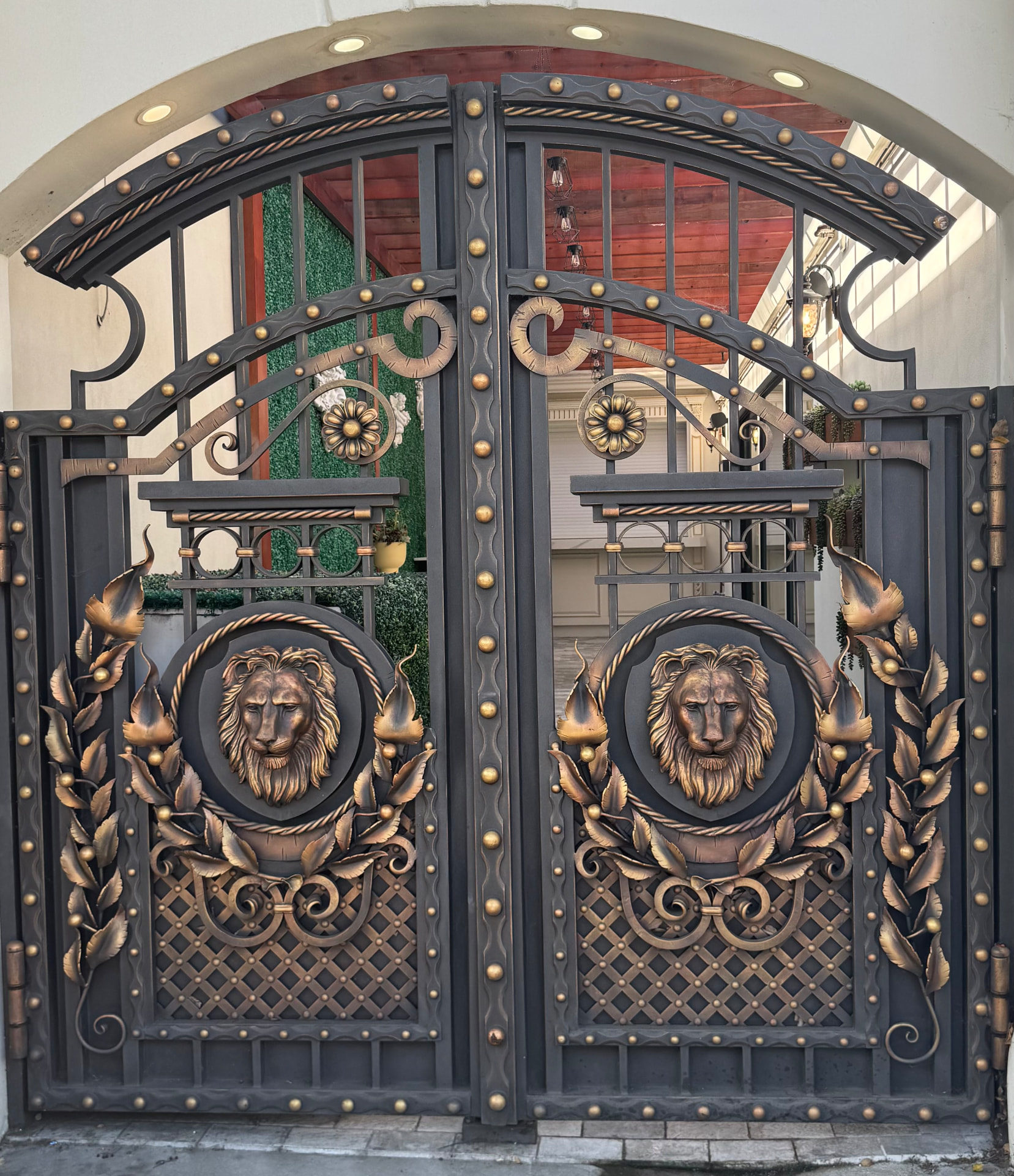 Ornate wrought iron gate with bronze lion heads and gold floral details