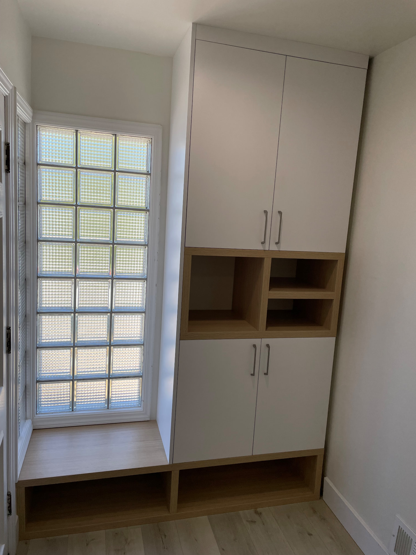 White and oak custom entryway cabinets with window bench seat