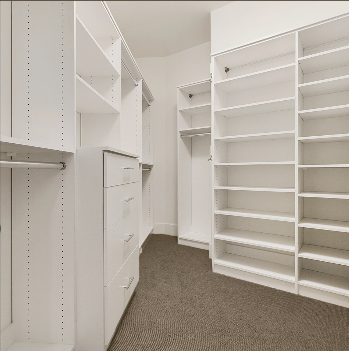 Custom white walk-in closet with adjustable shelving and drawer tower