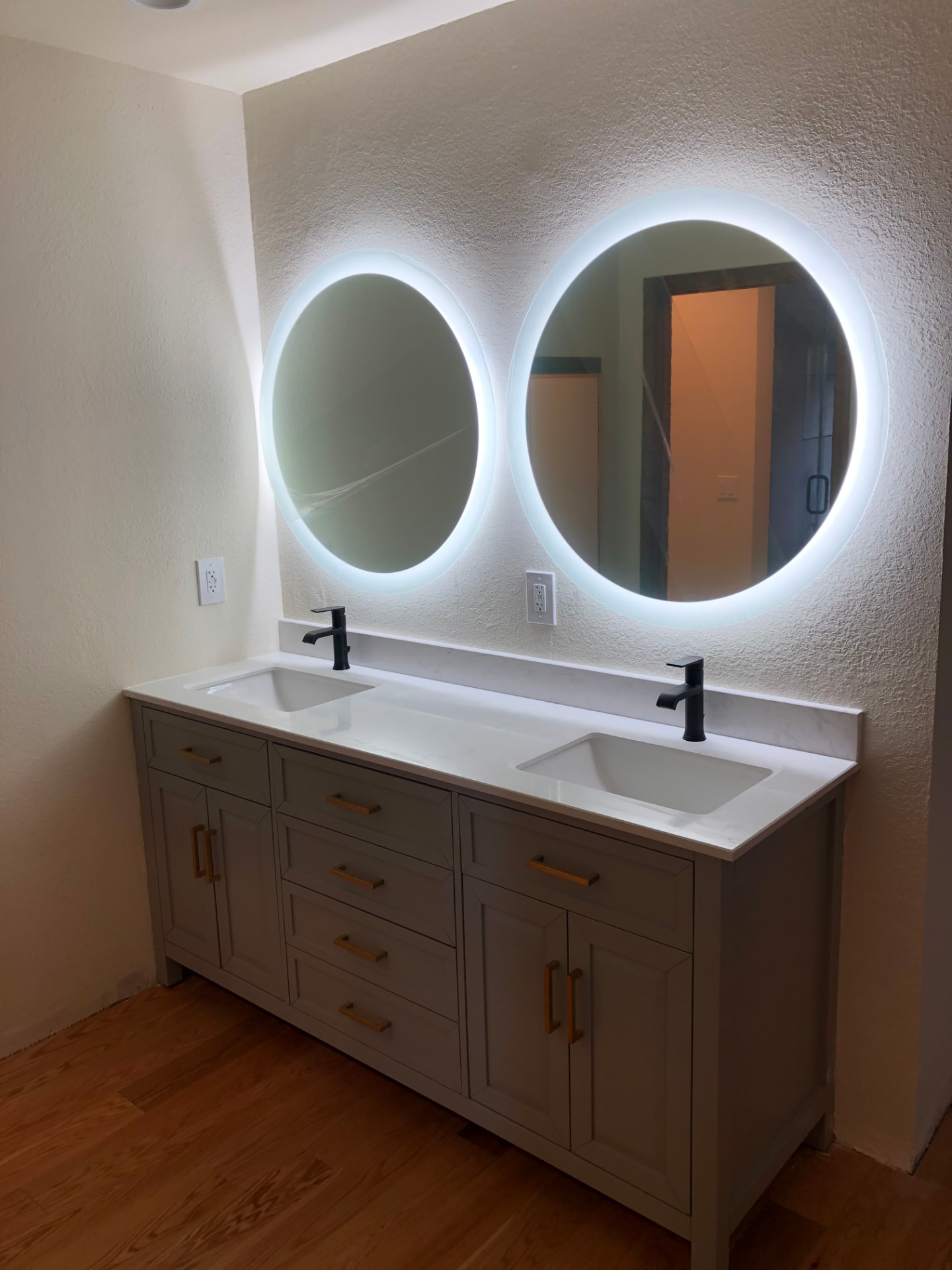Double vanity with backlit round mirrors and quartz countertop